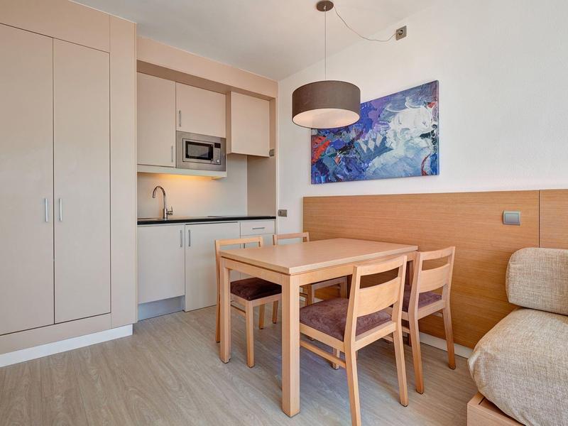 Angolo pranzo con tavolo in legno e cucina moderna integrata.