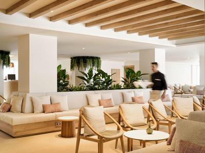 Helles, modernes Wohnzimmer mit Holzbalkendecke, Pflanzen und gemütlichen Sesseln in Beige- und Holztönen.