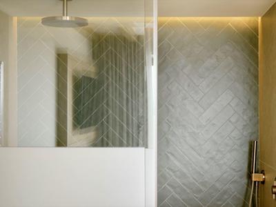 Modern designed shower with clear glass partitions and elegant gray tiles.
