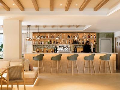 Modern hotel bar with wooden counter, bar stools, and welcoming atmosphere.