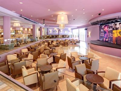 Large, modern hotel lobby area with many beige armchairs and a cozy atmosphere.