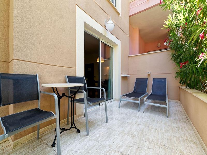 Small balcony with four blue chairs, a round table, and plants on the side