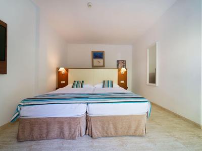 Una camera d'albergo semplicemente arredata con due letti singoli e pareti bianche.