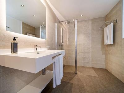 Modern bathroom with large mirror wall, sink, and walk-in shower.