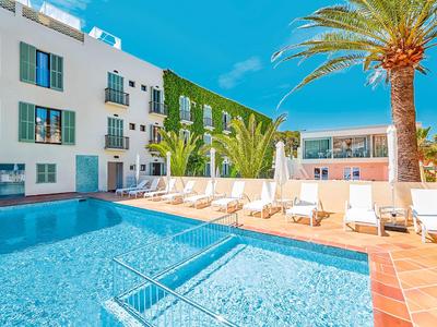 Moderner Hotelpoolbereich mit Liegestühlen und Palmen unter klarem Himmel.