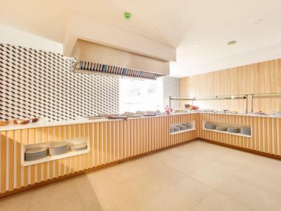 Modern, bright hotel kitchen with wooden cabinets and tiled backsplash.