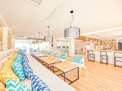 Světlý hotelový salonek s barevnými polštáři a moderními stoly