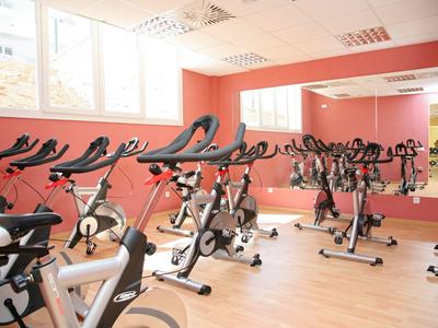 Vue intérieure d'une salle de sport avec plusieurs vélos d'exercice devant un grand miroir.
