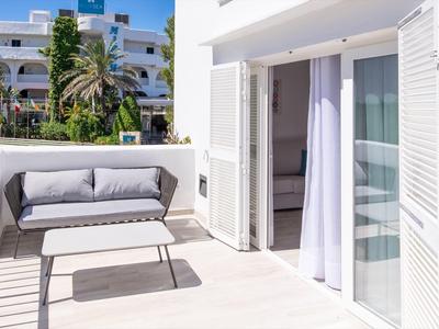 Terrace with white sofa and table in front of a hotel room with open sliding door