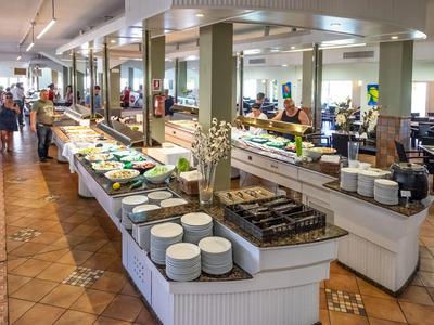 Cozy hotel dining area with buffet and guests selecting food.