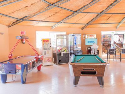 Recreatieruimte met luchtshockey- en pooltafels in een lichte kamer met oranje muren.