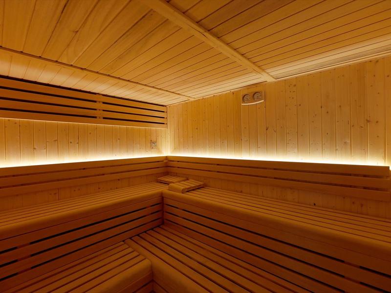 Interior view of a well-lit sauna with wooden paneling and benches.