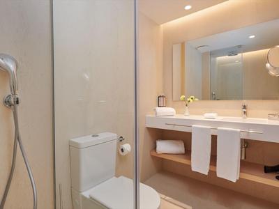 Modern bathroom with shower, toilet, and sink under a lit mirror.