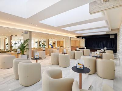 Modern, bright event space with comfortable armchairs and tables in neutral tones.