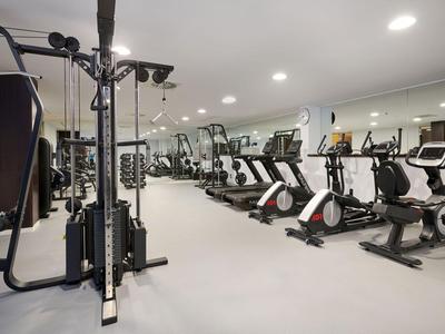 Moderner Fitnessraum mit verschiedenen Trainingsgeräten und Fahrrädern in einem hellen Raum.