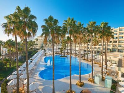 Großer Hotelpool mit Palmen und Liegestühlen an einem sonnigen Tag