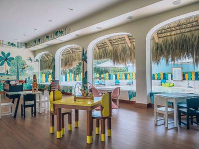 Intérieur lumineux de restaurant avec des chaises colorées et vue sur une piscine et une plage