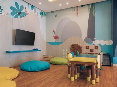 Salle de jeux colorée pour enfants avec petites tables, coussins et décorations murales dans l'hôtel.