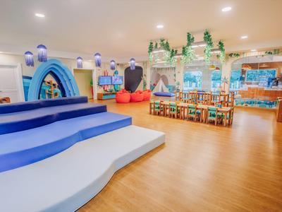 Espace de jeu lumineux et adapté aux enfants avec mobilier coloré et décors thématiques.