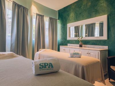A relaxing spa room with two treatment beds and soothing green decor.