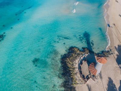 Aerial view of a lighthouse on the beach with clear turquoise water.
