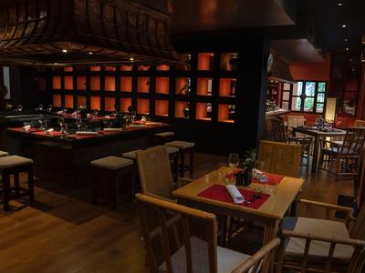 Dark, cozy restaurant with wooden tables, chairs, and subtle lighting.