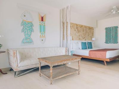 Bright room with bed, sofa, table, and Mediterranean wall decor in a hotel room.