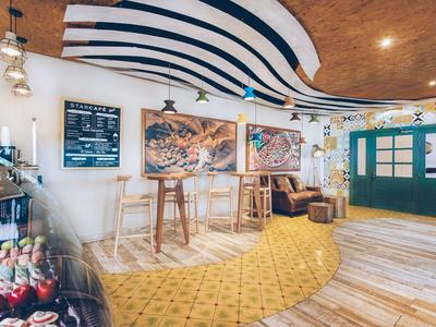 Cozy hotel lounge area with wooden floors, high stools, sofas, and striking ceiling lighting.