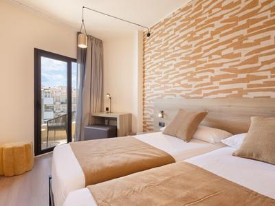 Modern hotel room with two single beds and a view of the city.