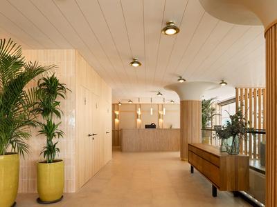 Bright hotel corridor with brown plant pots and wooden wall elements.
