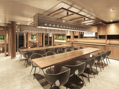 Modern dining room with long tables, black chairs, and warm lighting in a hotel setting.