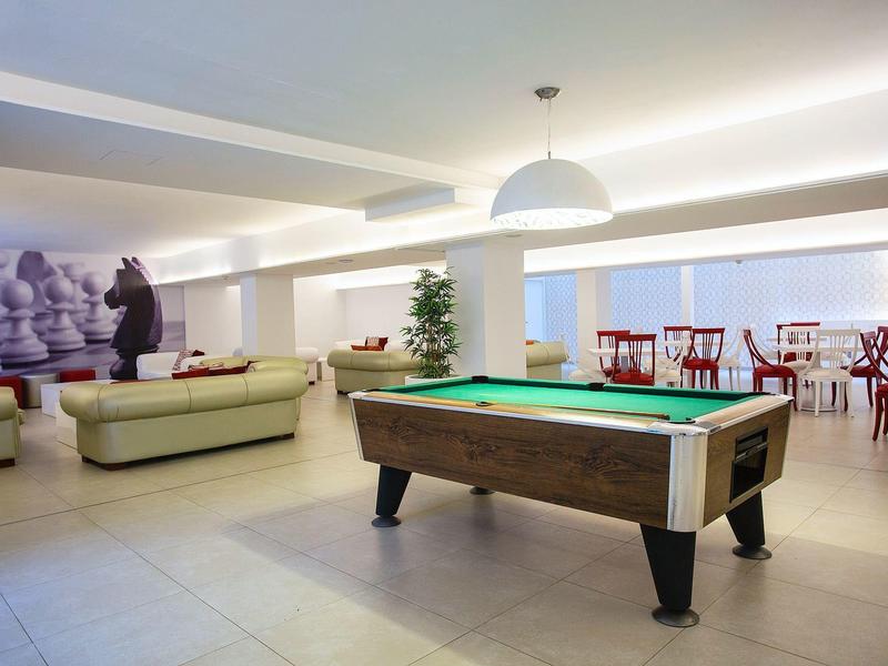 Modern lounge area with pool table, sofas, and seating in a bright hotel room.