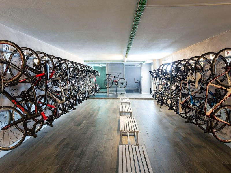 Bike storage room with two rows of bicycles hanging on walls and two benches in the center.