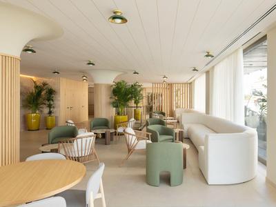 Bright, modern hotel lounge area with seating groups and large windows.