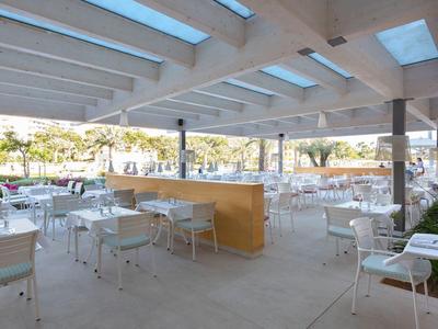 Open, modern outdoor restaurant area with white chairs and tables.