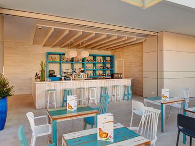 Modern café with bar area, blue accents, light wood paneling, and indoor seating.