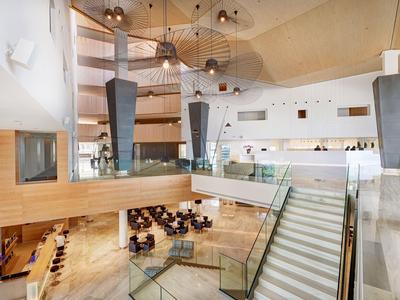 Heller, moderner Hotellobbybereich mit Holzvertäfelungen, Treppe und Sitzbereichen im unteren Bereich.