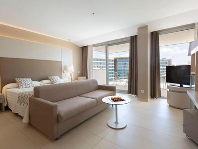 Modernes Hotelzimmer mit Doppelbett, Sofa und großem Fenster mit Stadtausblick.