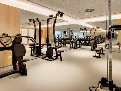 Moderner Fitnessraum mit verschiedenen Trainingsgeräten in hellem, geräumigem Raum.
