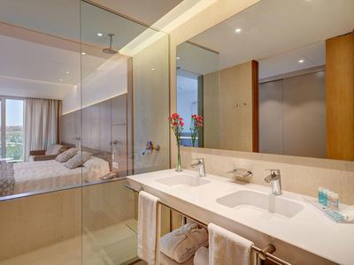 Modernes Hotelbadezimmer mit Doppelwaschbecken und Blick in ein Schlafzimmer.