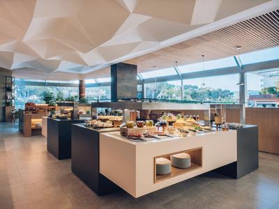 Modern buffet area with a variety of food on white counters in a spacious, well-lit room.