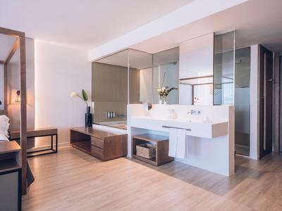 Modern bathroom with a large bathtub, double sink vanity, and wood flooring