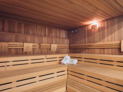 Spacious wooden sauna with benches and towels on a bench.