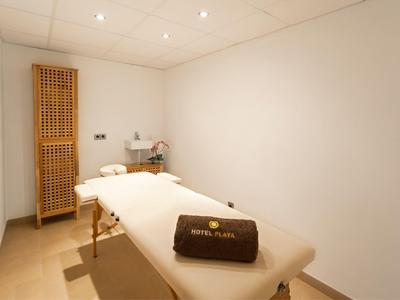 A serene massage room with a white massage table and a dark brown hotel pillow.