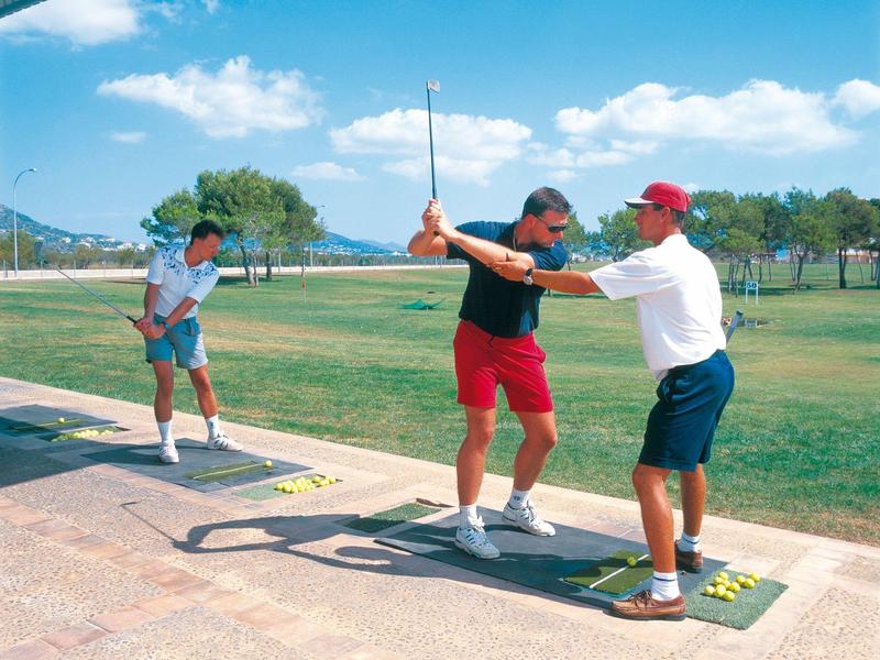 Golfinstructeur geeft les aan leerlingen bij een zonnige driving range.