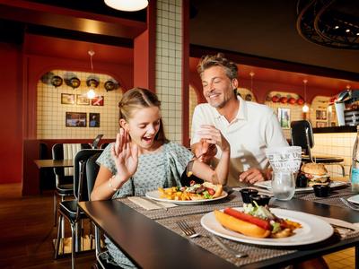 Father and daughter happily eating in a cozy restaurant.