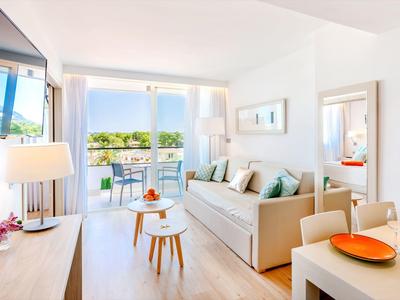 Helles Wohnzimmer mit Sofa, Couchtischen und Zugang zu Balkon mit Meerblick.