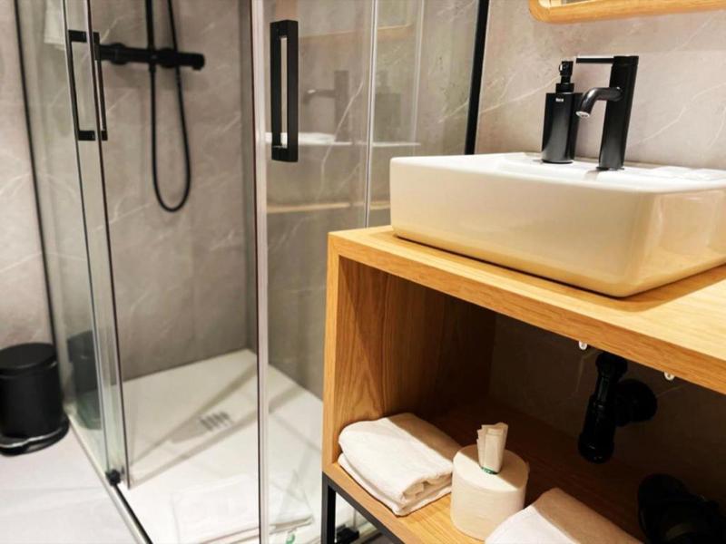 Moderne badkamer met glazen douche en wastafel op houten plank