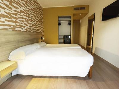 Modern hotelkamer met tweepersoonsbed, wanddecoratie, wand-tv en houten vloer.