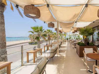 Offenes Restaurant am Strand mit weißen Sonnensegeln und Blick auf das Meer.